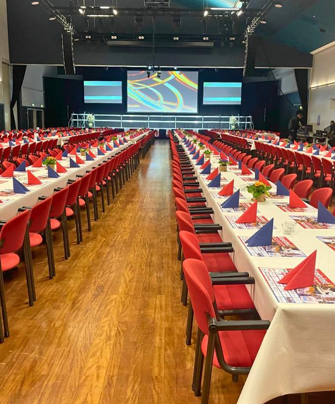 Sal A med bordopstilling, røde stole og scene til konference, årsmøde eller fagligt program
