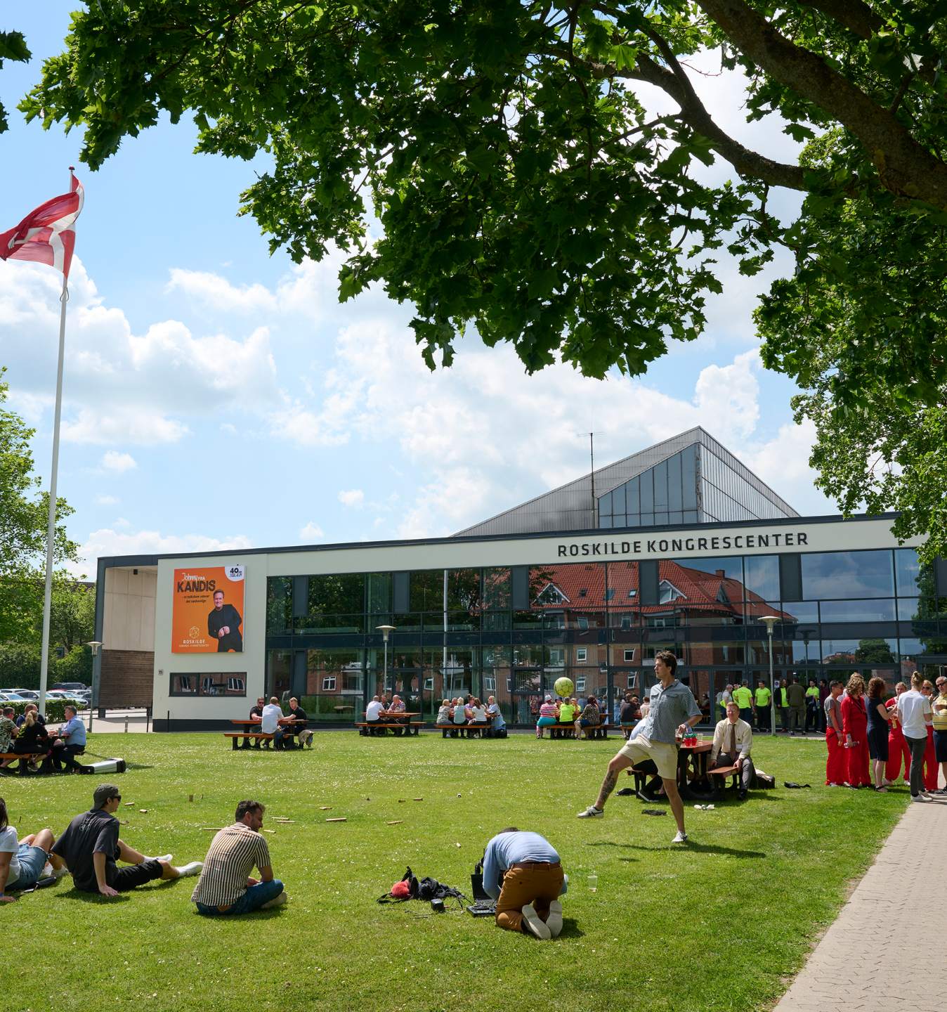 Facade af Roskilde Kongrescenter med flagstang og plæne foran indgangen