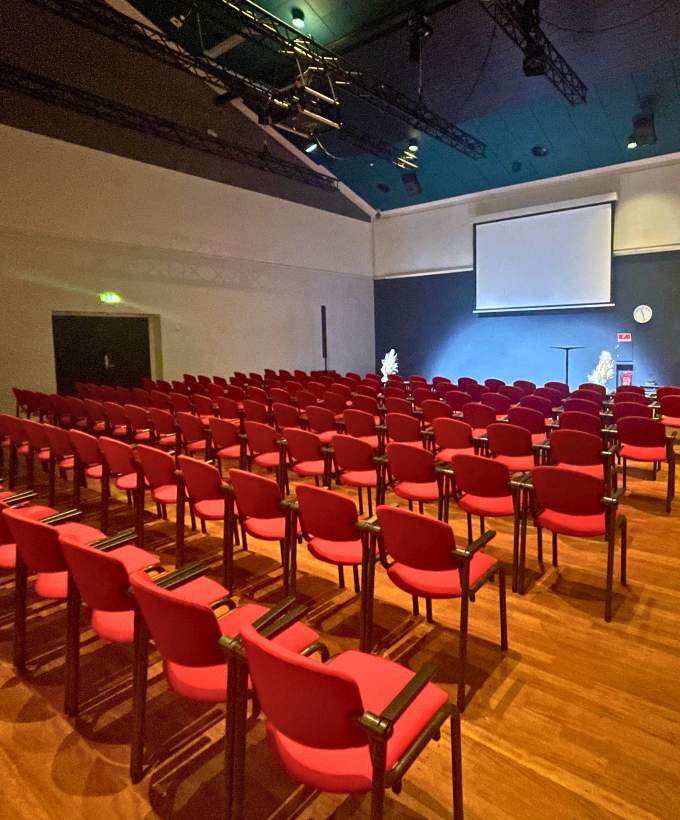Sal A2 med stoleopstilling, lærred og sceneområde til oplæg eller præsentation