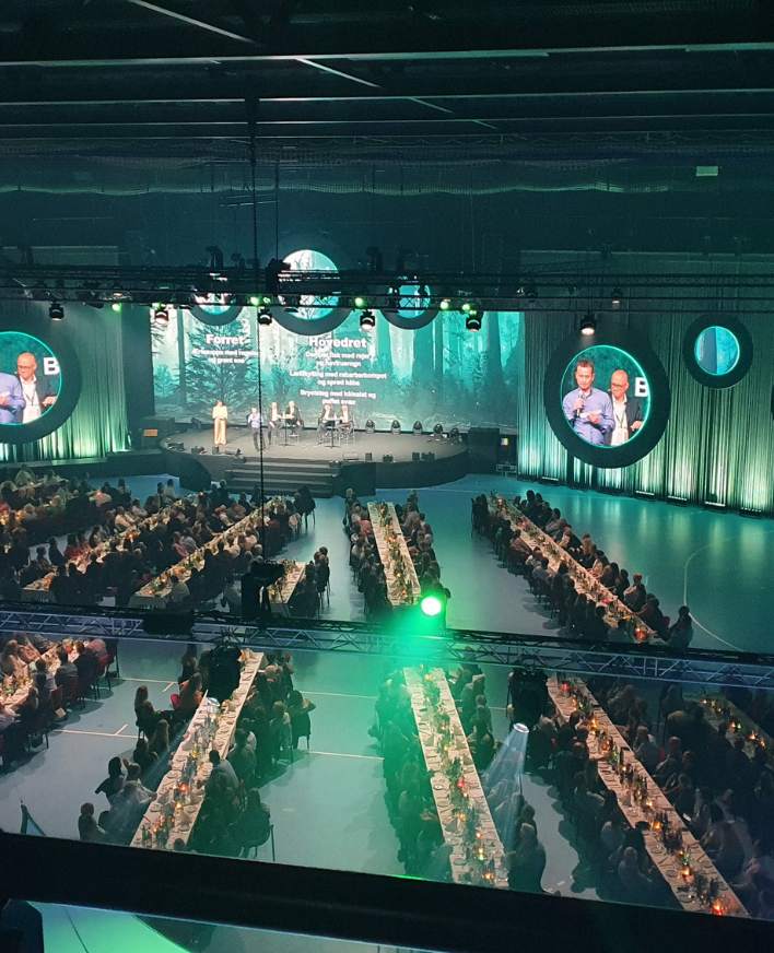 Stor konference i Roskilde Kongres- Idrætscenter med lange rækker af borde, samt flot professionelt lys og lydopsætning.